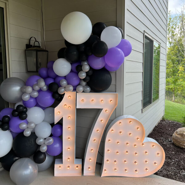 The numbers '17' in marquee letters with a heart next to them and garland balloons behind it