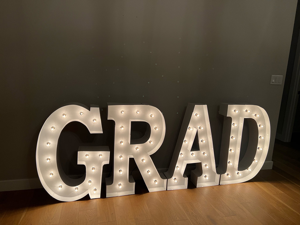 The word 'grad' in lit marquee letters with white bulbs