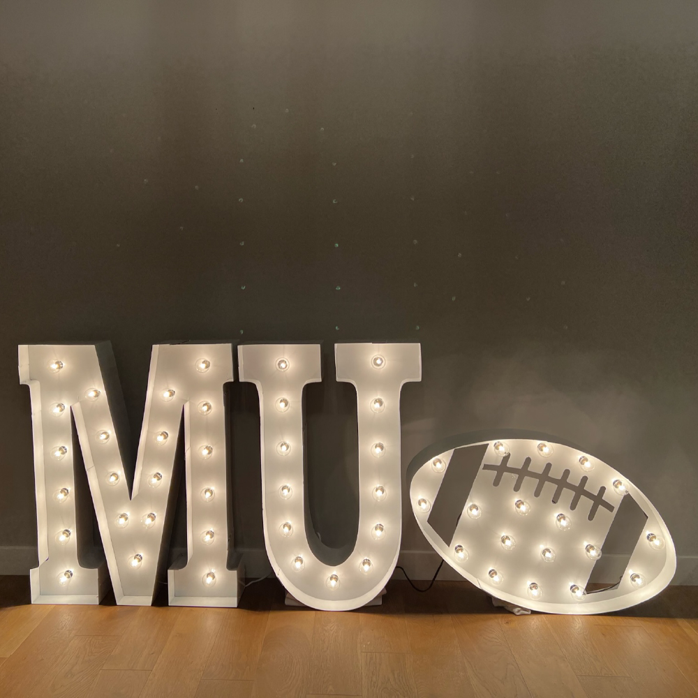 "MU" in lit marquee letters with a football
