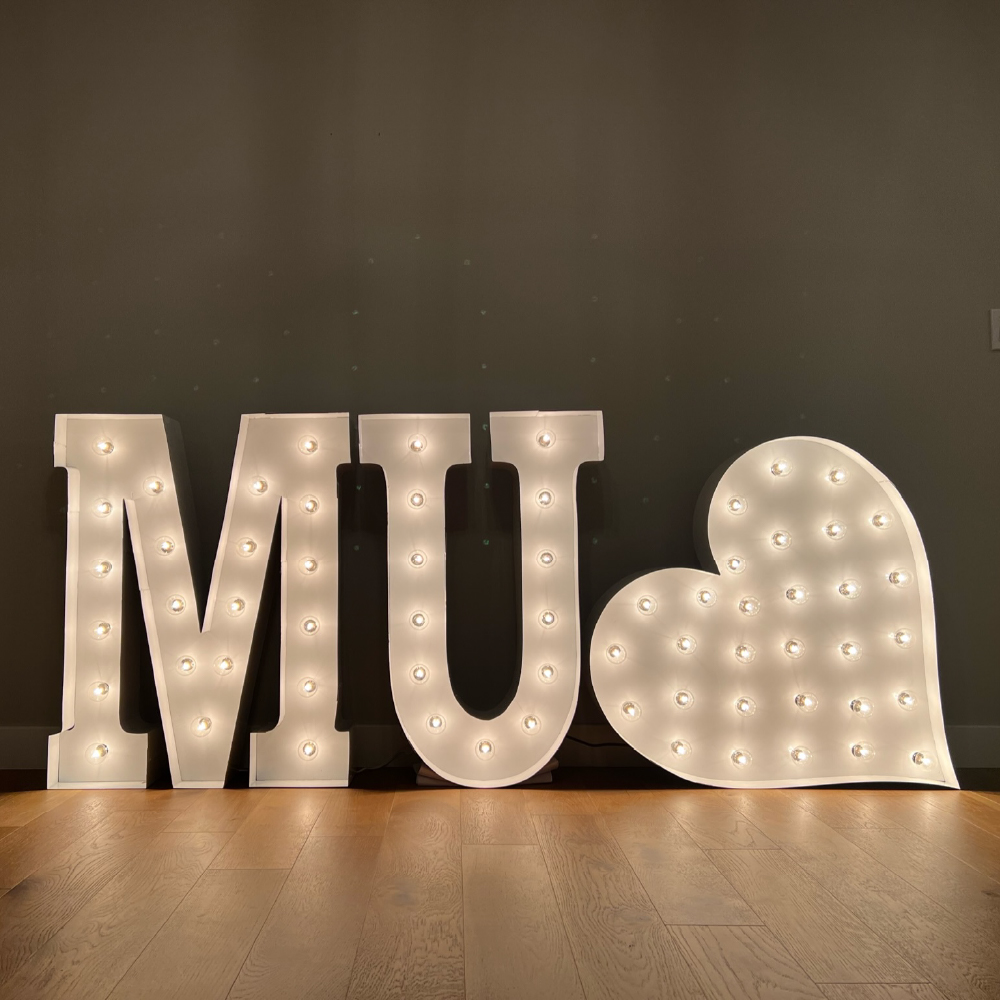"MU" in lit marquee letters with a heart