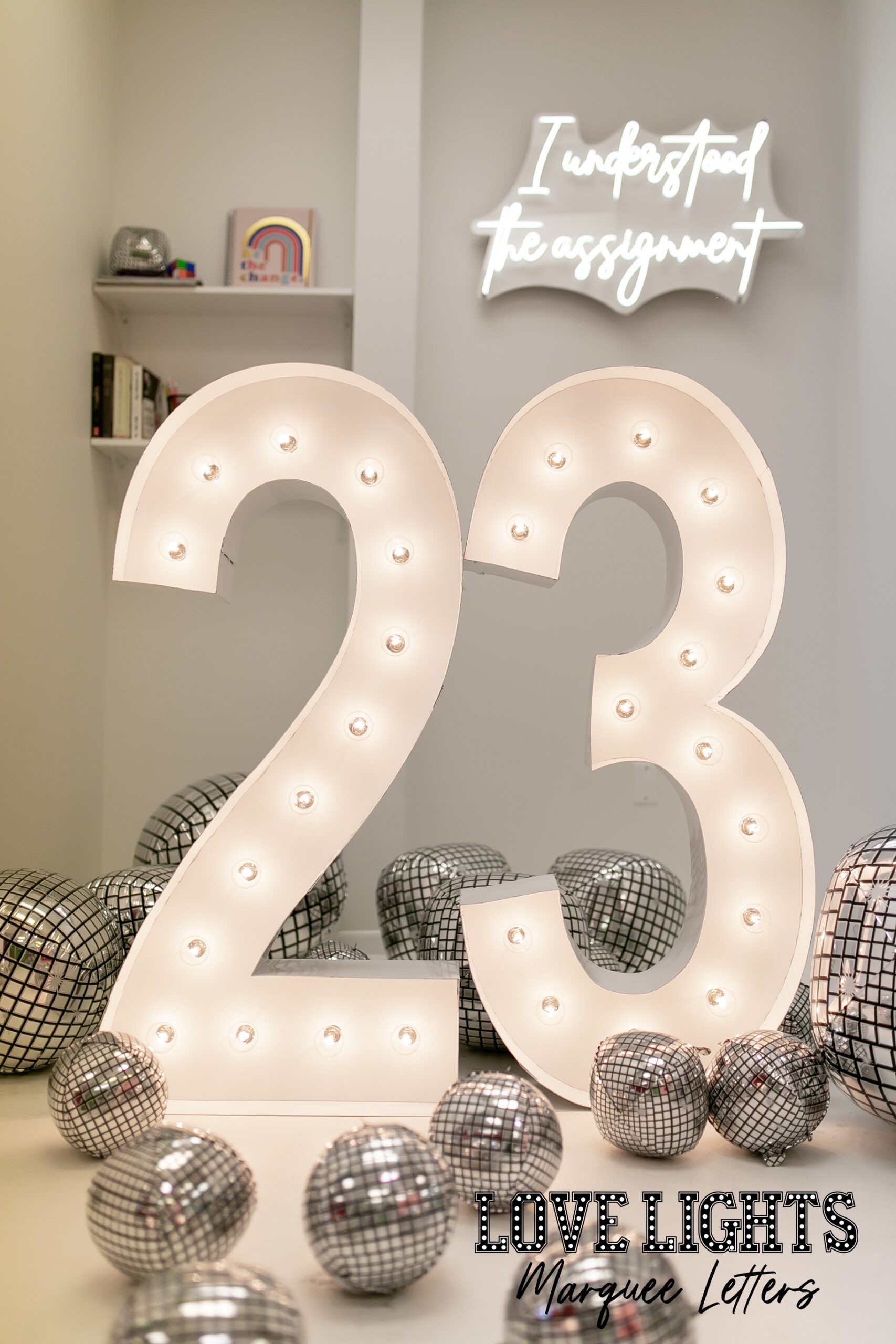 23 in lit marquee letters in a room with balloons