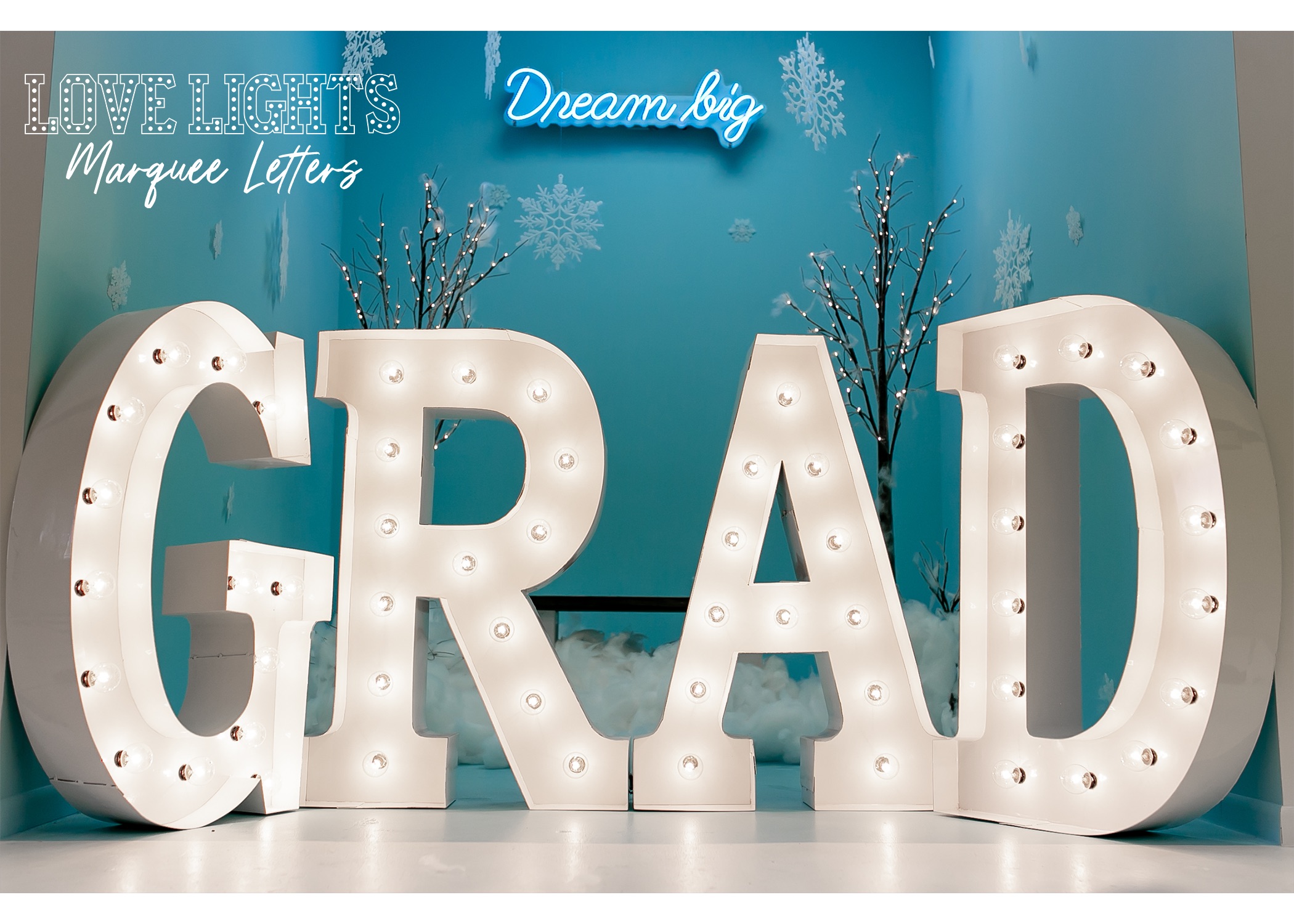Grad in lit marquee letters in blue winter decorated room with words Dream big