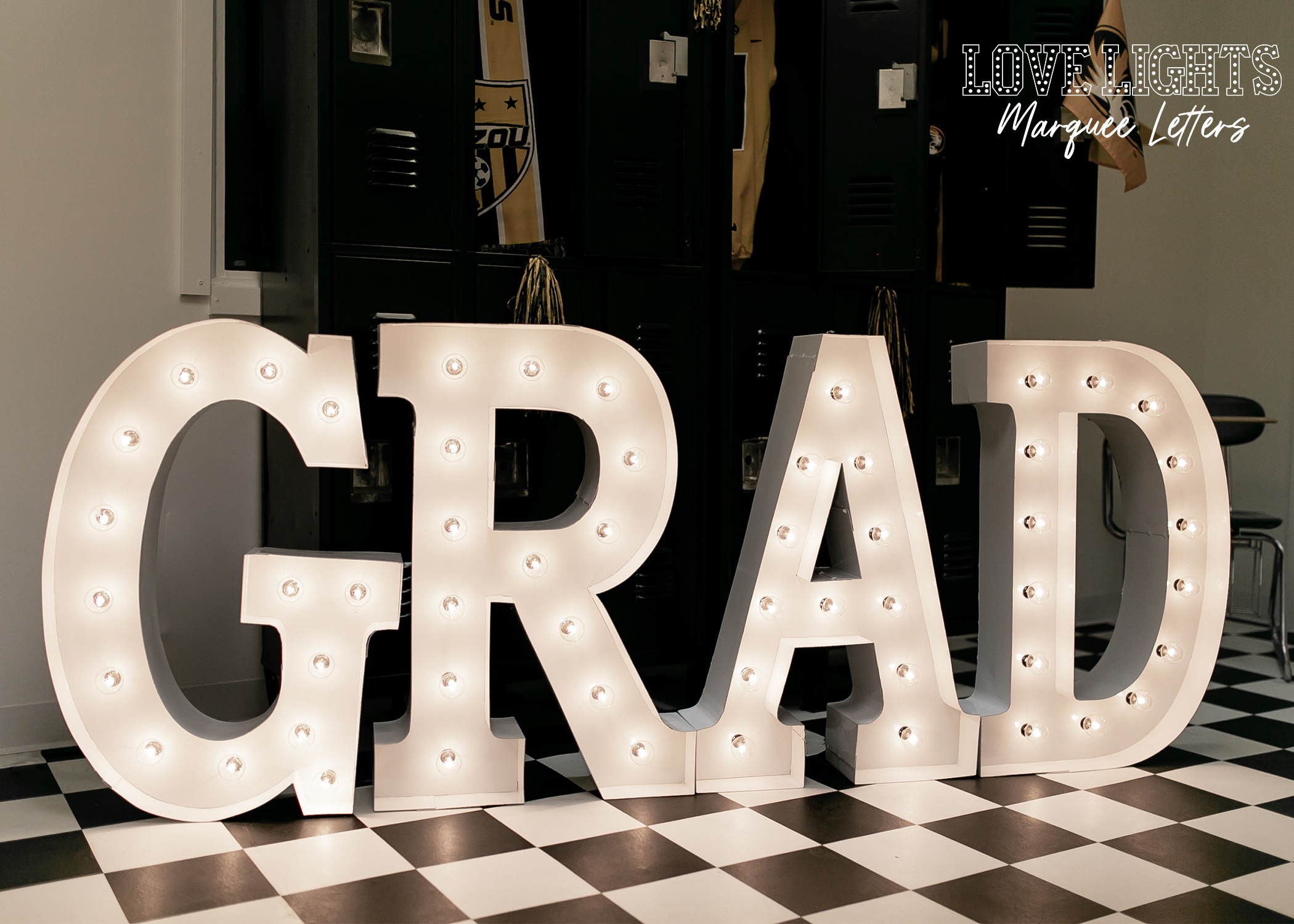GRAD in lit marquee letters on checkered floor