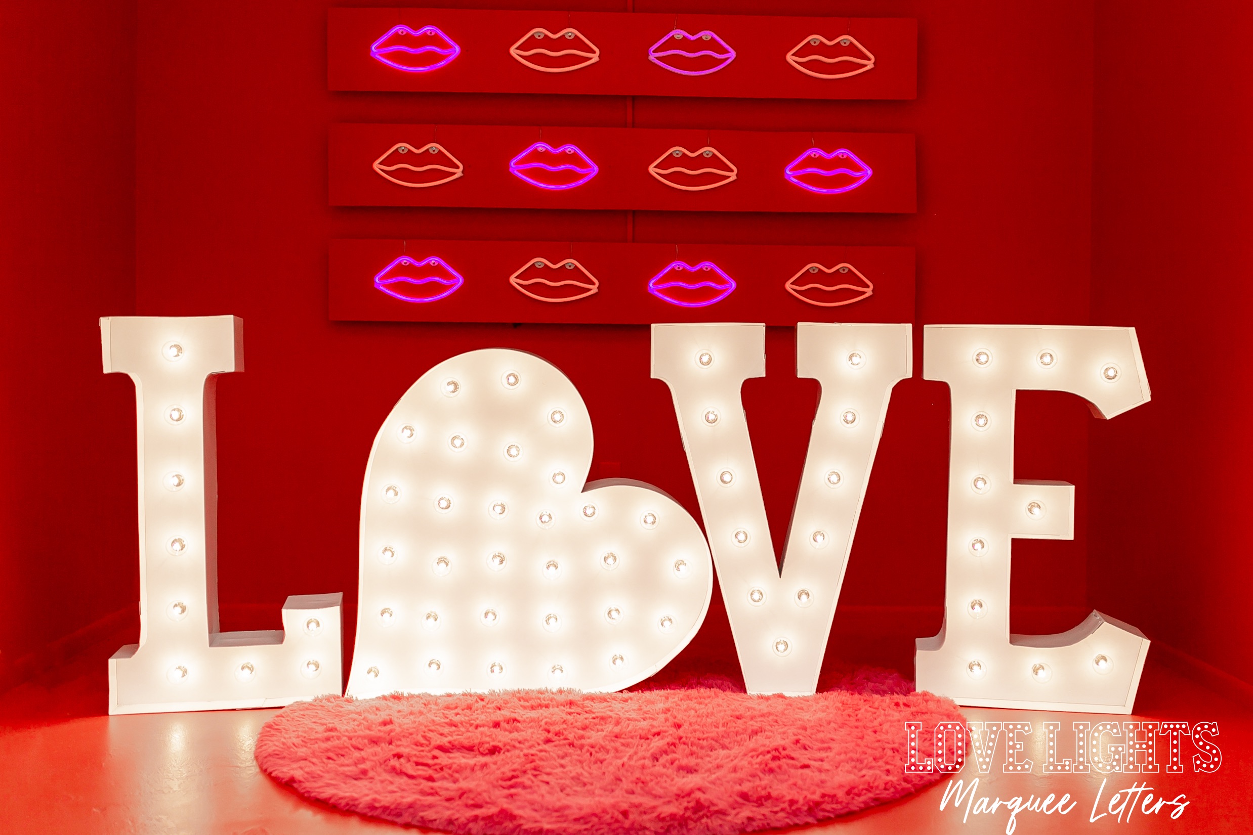 Love in lit marquee letters with a heart in lit marquee letters for the 'O' in red room in front of LED lip lights