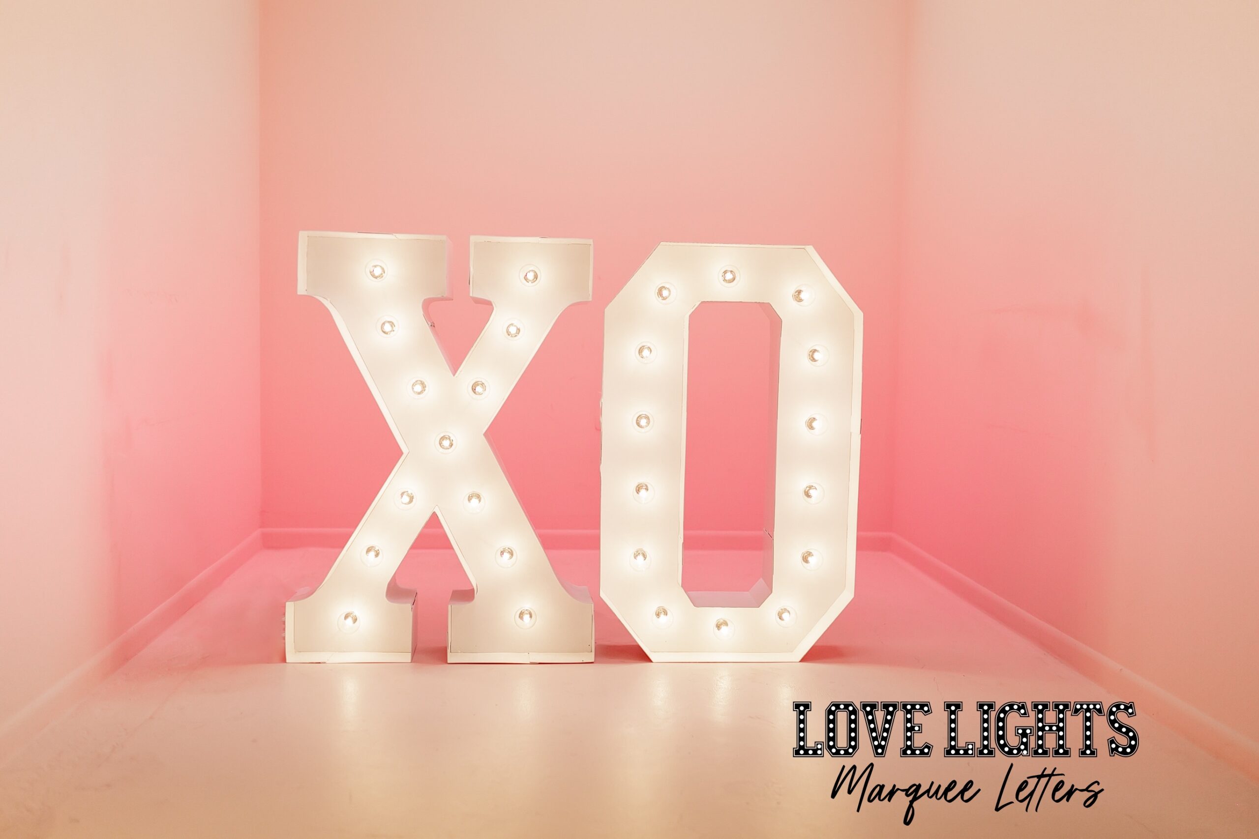 XO in lit marquee letters in a pink room